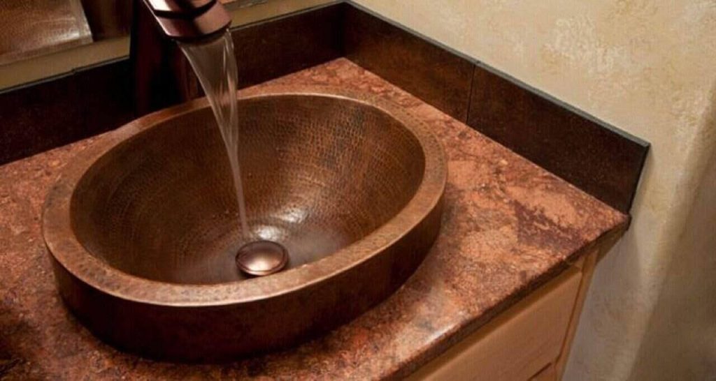 soft carbon filtered water running from tap on a wooden colored sink.