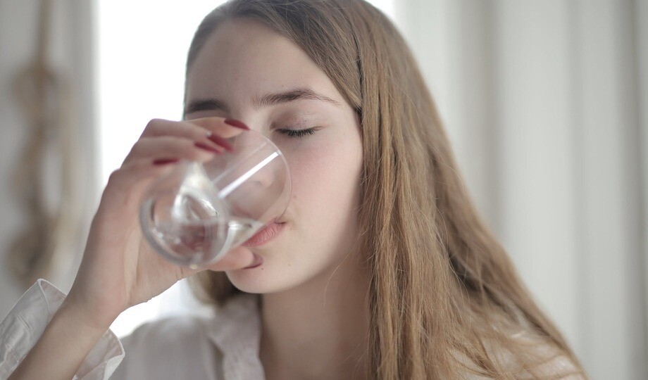 white blonde Girl drinking carbon filtered water from a glass